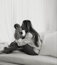 a woman sitting on top of a bed holding a stuffed animal next to her face