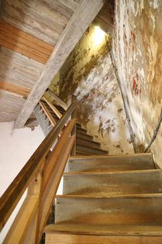 stairs leading up to the top of an old building with peeling paint and wood flooring