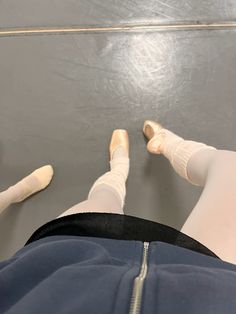 the legs and feet of a person in white socks, with one leg up on the ground