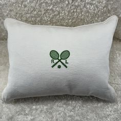 a white pillow with two tennis rackets on it