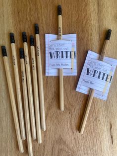 several pencils and some writing paper on a wooden table next to two small notepads