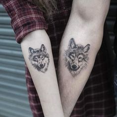 two tattoos on the arms of people that are holding each other's hands with wolf heads