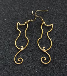 the gold earrings are shaped like a cat's head and have long curved tails