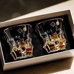 two shot glasses in a silver box with gold trim