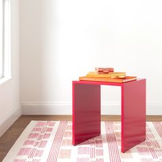 a red table sitting on top of a white rug