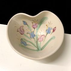 a heart shaped bowl with flowers painted on it