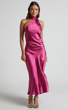 a woman is wearing a pink dress with a halter neck and side slits