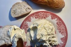 a red plate topped with cream next to two loaves of bread