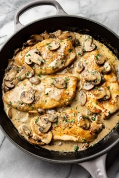 chicken with mushrooms and gravy in a skillet on a marble countertop