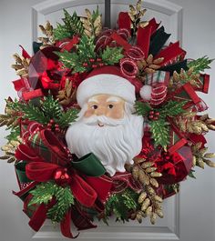 a wreath with a santa clause on it is hanging from the front door, decorated with red and green ribbons