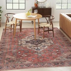 a living room area with a couch, table and chairs in it on top of a rug