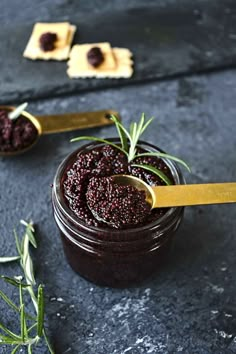 two small jars filled with jam on top of a black table next to crackers