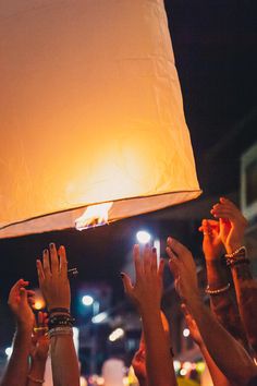 a group of people holding up their hands in front of a sky lantern