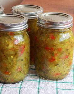 four jars filled with pickles sitting on top of a table