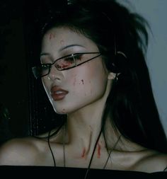 a woman with blood on her face and eyeglasses is staring at the camera