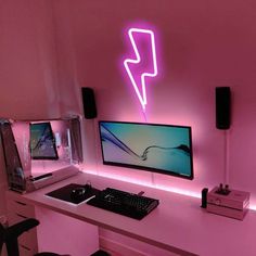 a computer monitor sitting on top of a desk next to a keyboard and mouse in front of a neon sign