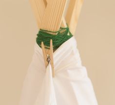 two wooden clothes pins are attached to a white dress with green string on the bottom