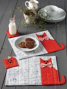 two cat placemats on a table with cookies and milk