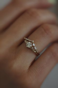 a woman's hand with a diamond ring on top of her finger and an engagement band