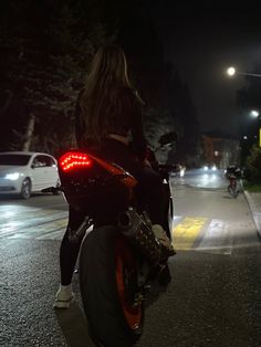 a woman riding on the back of a motorcycle at night