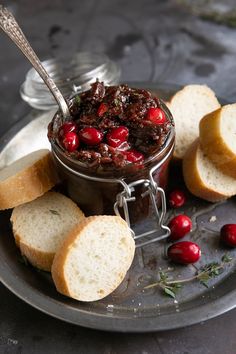 bread and cranberry spread on a plate with silver spoons next to it