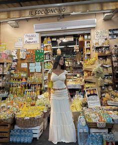 a woman standing in front of a store filled with food