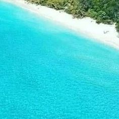 an aerial view of the ocean and beach with people walking on the sand in the water