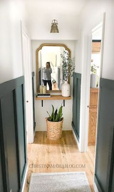 a woman is standing in the hallway looking at herself in the mirror