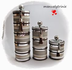 three silver canisters with tassels on them and a red heart in the background