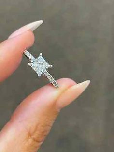 a woman's hand holding an engagement ring with a diamond cross on the side