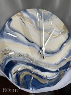 a clock made out of glass with blue and white swirls on the face is shown