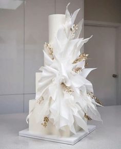 a three tiered white cake with gold leaf decorations