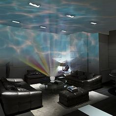 a living room with couches, tables and lamps on the ceiling is lit by colorful lights