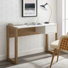 a white desk with a lamp on it in front of a brick wall and chair