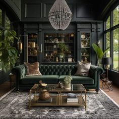 a living room filled with furniture and lots of green plants in the corner, along with a chandelier hanging from the ceiling