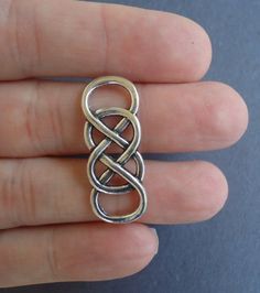 a person is holding a silver ring with an intertwined knot on it's side