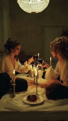 two women sitting at a table with candles in front of them