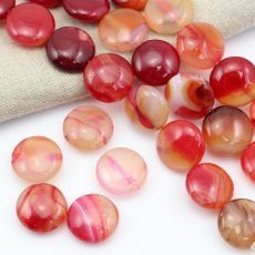 some red and brown beads are laying on a white surface next to a linen bag