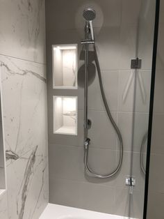 the shower head is mounted on the wall above the bathtub, and it's built - in shelves