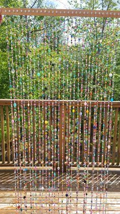 a wooden deck with beads hanging from it's sides and trees in the background