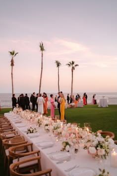 a long table is set up on the lawn for an outdoor wedding reception with palm trees in the background