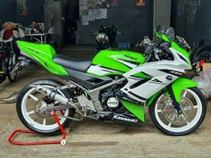 a green and white motorcycle parked next to other motorcycles