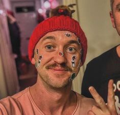 two men with face paint on their faces posing for the camera, one holding up his peace sign