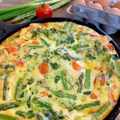 an omelet with asparagus, tomatoes and green beans in a cast iron skillet