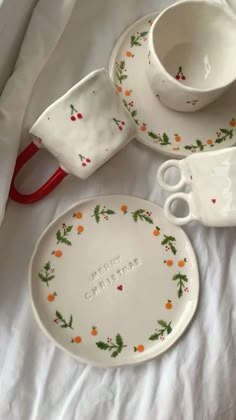 a white bed topped with dishes and cups