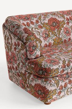 an upholstered floral print sofa with rolled arms and foot rests on the floor