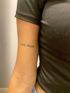 a woman's arm with the words love yourself tattooed on it in blue ink