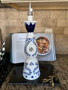 a blue and white vase sitting on top of a counter next to an open book