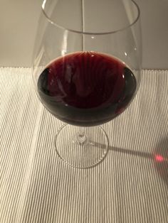 a close up of a wine glass with a red liquid in it on a table