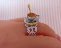 a miniature tea cup and saucer on someone's finger